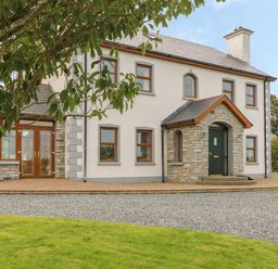 A two-story house with a stone porch and multiple windows with brown frames at Redford View in Culdaff County Donegal