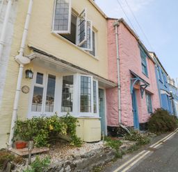 A row of colorful houses along a sloped street with plants outside at Pixie Cottage in Looe