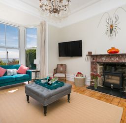 A living room with sofas a fireplace a wall mounted television and large windows at 6 Albany Terrace in St Ives