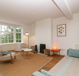A living room with armchairs a sofa a small round table a floor lamp and a large window at Tor Cottage in Colwall Herefordshire