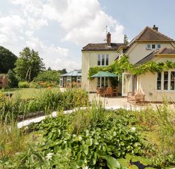 A garden pond with water lilies in front of a house with patio furniture at Valley House in Devizes