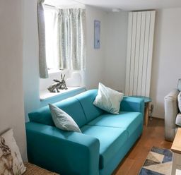 A living room with two sofas a wooden coffee table and decorative items on a window sill at Furneaux Hatch in Churchstow