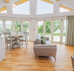 A living room and dining area with large windows overlooking greenery at Pen Bryn in Cyffylliog near Ruthin