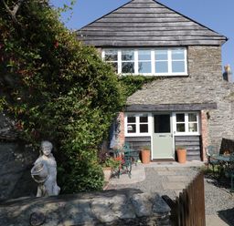Stone cottage with green door stone patio and garden statues at Crosscombe Barn in Loddiswell