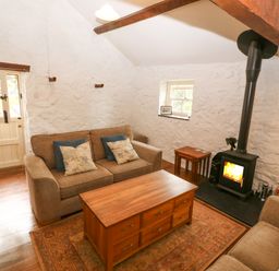 A sitting room with sofas coffee table and wood burning stove at Nant Bach Boduan near Nefyn