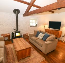 A living room with two sofas a wooden coffee table a wood stove and a television at Nant Bach in Boduan near Nefyn