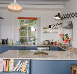 A kitchen with blue cabinets a marble countertop and a bookshelf at Wottonsbury in Ilsington