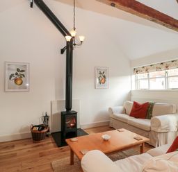 A living room with a wood stove and two sofas near a window at Toms Barn in Mudford Sock near Yeovil Somerset