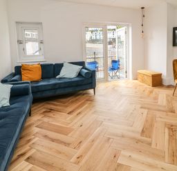 A living room with blue sofas and a small dining area near a balcony at Harbour Hideaway in Looe