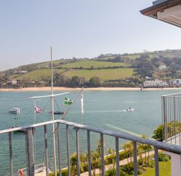 A view of a river with boats and a green hillside with houses seen from a balcony at 32 The Salcombe in Salcombe