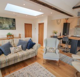 An open living room and kitchen with sofas a dining table and kitchen island at Border View Lodge in Llandrinio