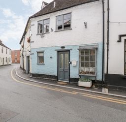 A street view of a cottage with a blue and white facade and a gray door at Cobblers Cottage in Upton Upon Severn