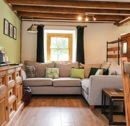 A living room with a gray sectional sofa and wooden furniture at Bwthyn Gwyn Tyn Y Pant in Boduan near Nefyn
