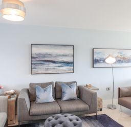 A living room with two grey sofas blue pillows a floor lamp and framed art on the wall at Chandlers Retreat in Newport Pembrokeshire