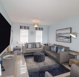 A living room with two sofas a large rug and a wall-mounted television at Chandlers Retreat in Newport Pembrokeshire