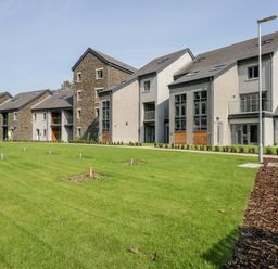 A grass lawn in front of modern apartment buildings at River View in Backbarrow