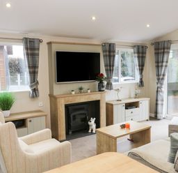 A living room with a fireplace television armchairs coffee table and large windows at Huckleberry in Runswick Bay near Staithes