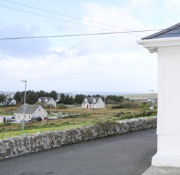 A view of houses fields and trees from a roadside near a white house at Ard an Phiobaire in An Luinnigh near Derrybeg County Donegal