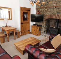 A living room with leather sofas wooden coffee table fireplace and dining table at The Old Carriage House in Clappersgate
