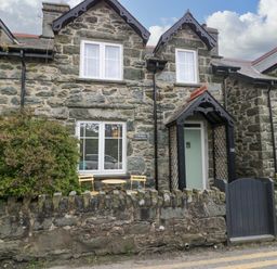 An exterior view of a stone house with a garden area at Y Bwthyn in Llanbedr