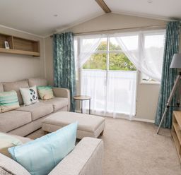 A living room with beige sofas and cushions a wooden coffee table floor lamp and television at Ystwyth 26 in Borth