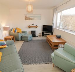 A living room with sofas armchair coffee table and television at Seaside retreat in Porthmadog