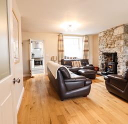 A living room with brown leather sofas a stone fireplace and wooden floor at Artro View in Llanbedr