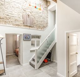 A hallway with stairs and doorways leading to other rooms and a stone wall at The Old Coach House in Braunton