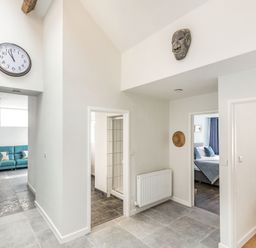 A hallway with a wall clock and two doorways showing a bathroom and a bedroom at The Old Coach House in Braunton