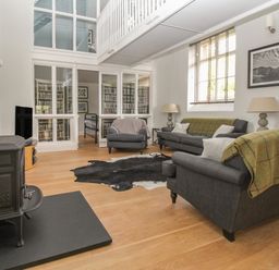 A living room with gray sofas and a black wood stove at St Marys Chapel in West Lulworth