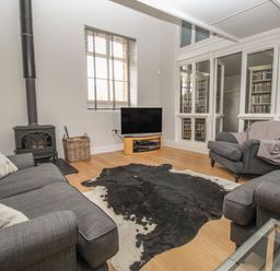 A living room with sofas tv wood burner and animal hide rug at St Marys Chapel in West Lulworth