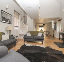A living room with two grey sofas a cowhide rug a wood stove and a dining area in the background at St Marys Chapel in West Lulworth