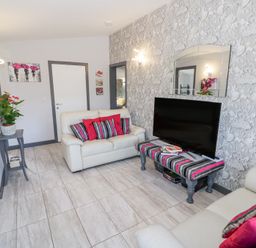 A living room with two white sofas and a striped table holding a television at The Garden House in Upper Quinton near Lower Quinton