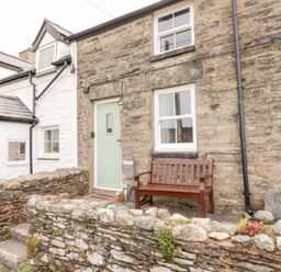 Stone cottage exterior with a light green door wooden bench and stone wall at Afallon in Penmachno
