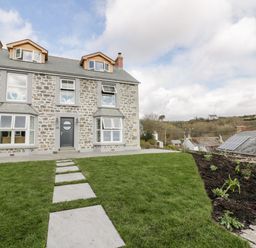 A stone house with a pathway through a grassy lawn and garden at Louvain in Cadgwith near Ruan Minor