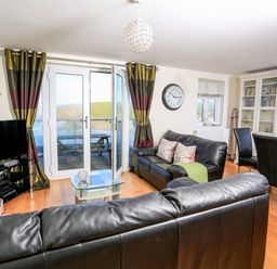 A living room with leather sofas a glass coffee table a television and dining area at 2 The Bay in Bigbury