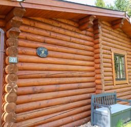 An exterior view of a log cabin with a bench and two windows at Jalan End in Felton
