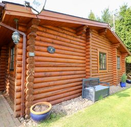 A wooden log cabin with windows and potted plants on a lawn at Jalan End in Felton