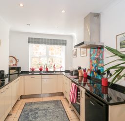 A kitchen with cabinets black countertops a stove a hood and a window with plants on the sill at The Hideaway in Malvern