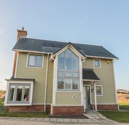 A two-story house with large windows and solar panels on the roof at The Deck House in Beadnell