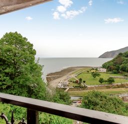 A view of trees coast and buildings from a balcony at Clooneavin Apartment 4 in Lynmouth