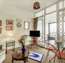 A living room with a sofa table lamps a television glass dining table with chairs and a balcony at Clooneavin Apartment 4 in Lynmouth