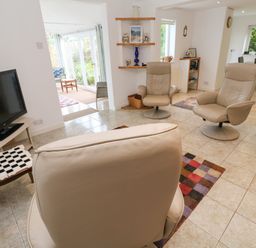 A living room with leather chairs a television and side table with a lamp at Alice Cottage in Wheal Kitty near St Agnes