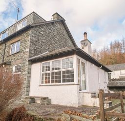 An exterior view of a stone and white plaster house with multiple windows and a chimney at Plumblands in Chapel Stile