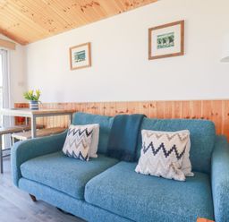 A living room with a blue sofa two cushions a floor lamp and a table with stools at 194 Atlantic Bays Atlantic Bays Holiday Park near St Merryn