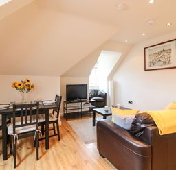 A living room with a dining table and chairs a sofa a coffee table a television and an armchair at Harbour Reach 6 Weymouth