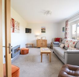 A living room with a gray sofa a wooden coffee table and armchairs at Berwyn View Trelydan near Welshpool