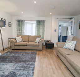 A living room with two sofas pillows curtains a floor lamp and a rug at Beach Cottage in Portreath