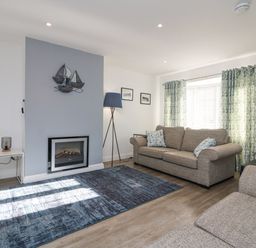 A living room with two sofas a fireplace and patterned curtains at Beach Cottage in Portreath