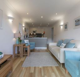 A living room with a sofa armchair rug and kitchen area at Atlantis in St Ives